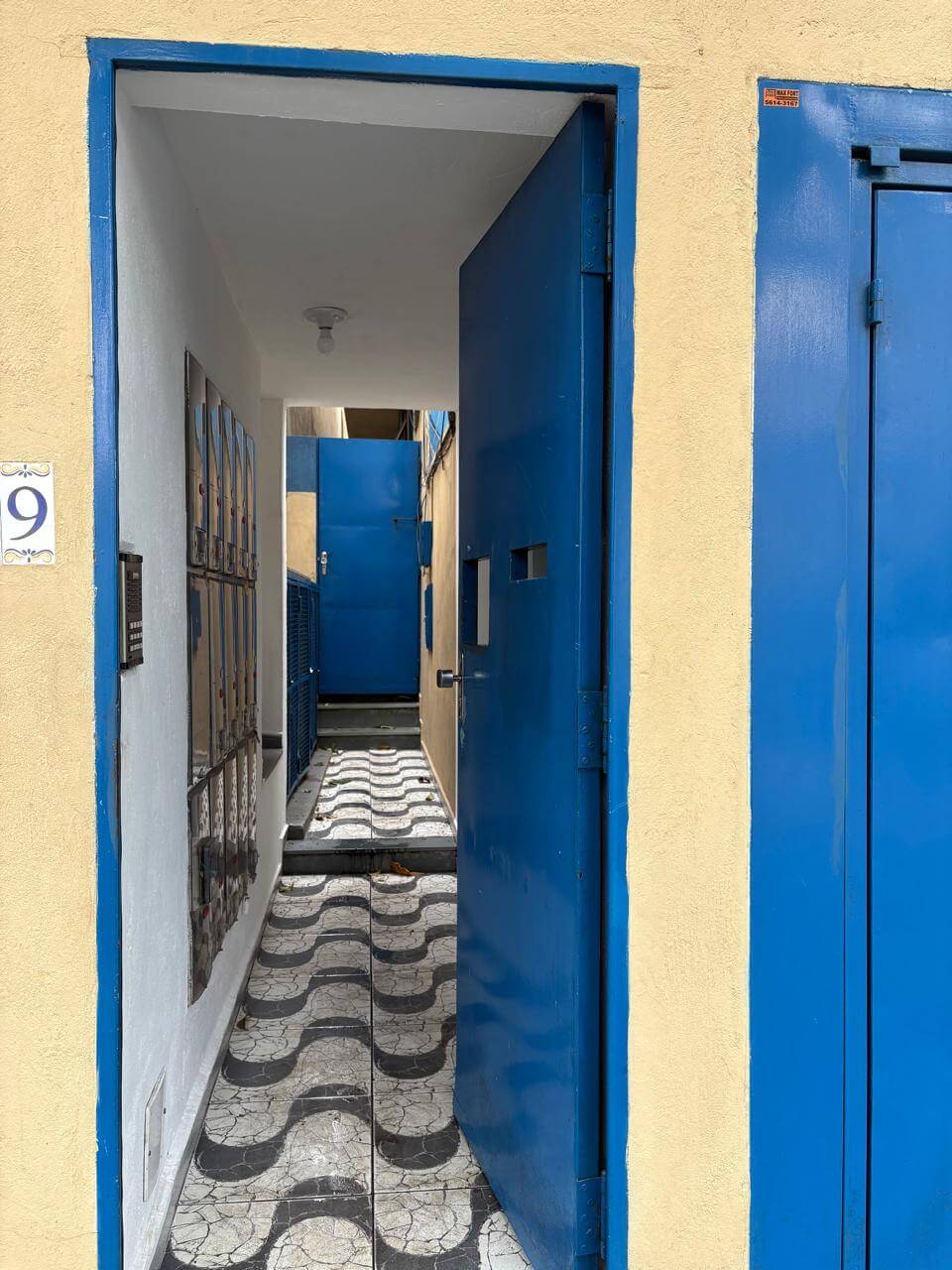 Interior de kitnet mobiliada com corredor iluminado e acabamento moderno em São Paulo com porta de segurança